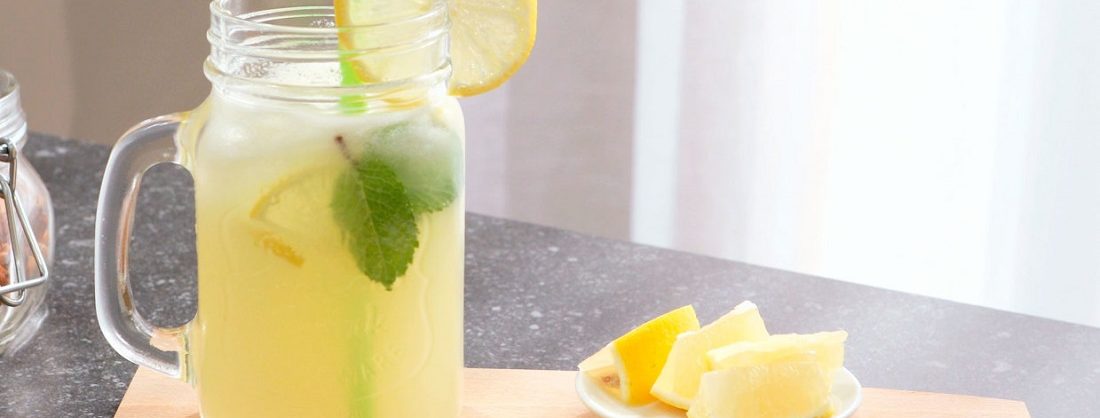 Jarra de limonada fría con rodajas de limón flotando y mucho hielo