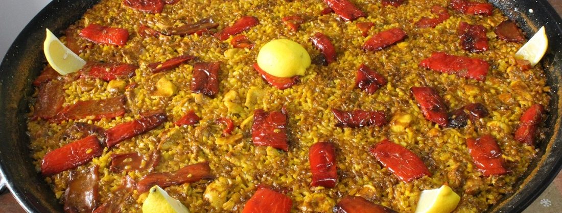 Paella de arroz con pollo y tiras de pimiento rojo
