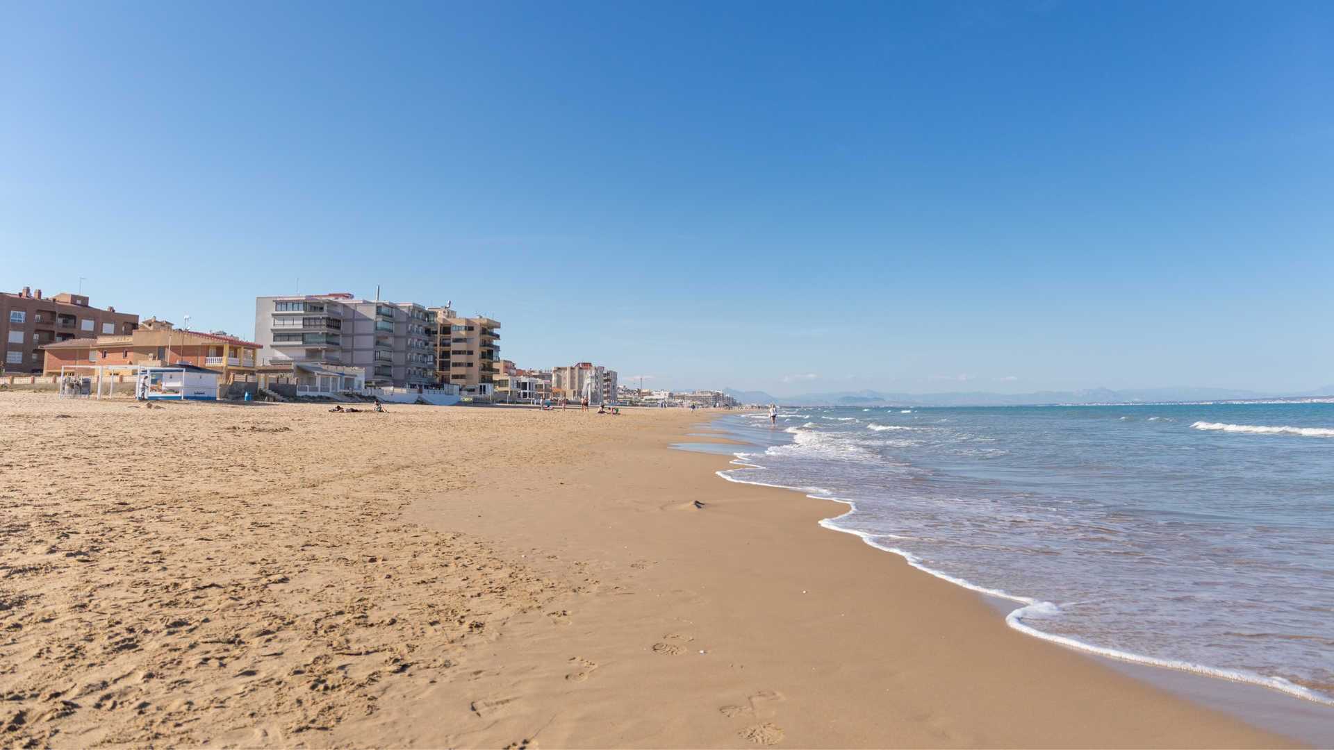 Bañistas disfrutando de la Playa de la Roqueta en un día soleado