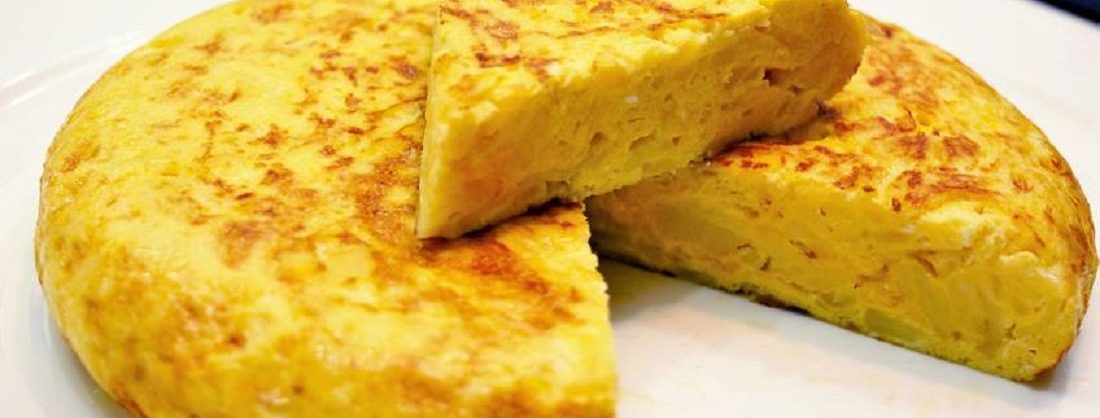 Tortilla de patatas gruesa y dorada servida en un plato blanco