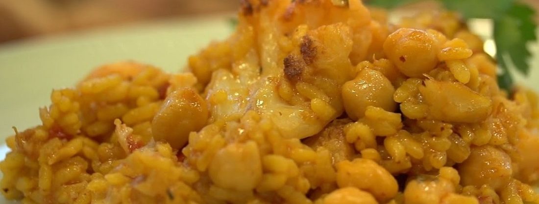 Paella de arroz con bacalao, garbanzos y cabeza de ajos asada