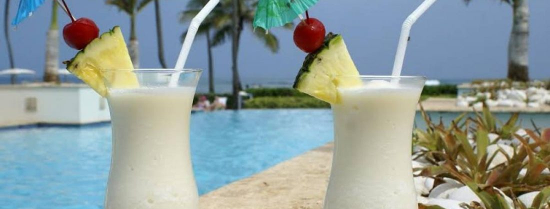 Copa de piña colada adornada con un trozo de piña y una pajita